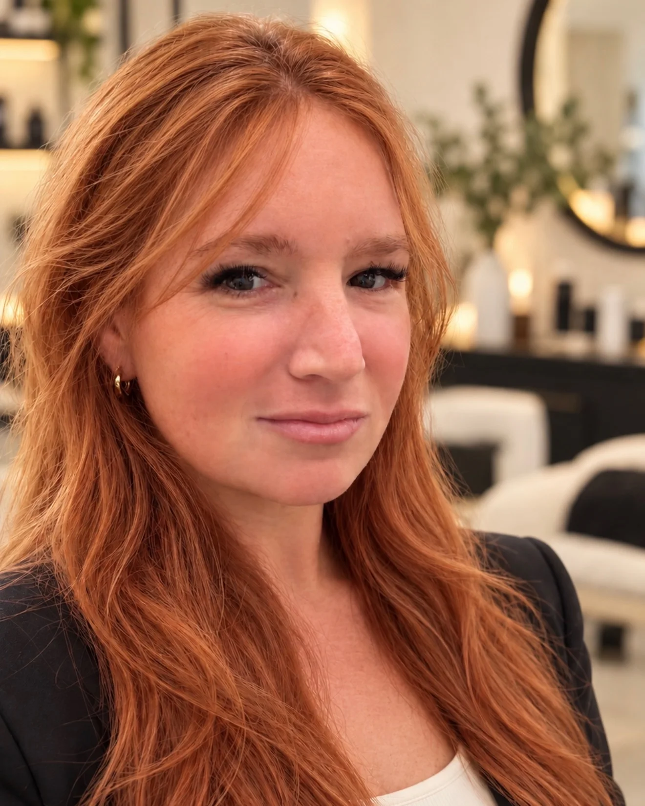 Lisa, owner of Lash L’Atelier, with long copper-red hair and a black blazer, in the studio